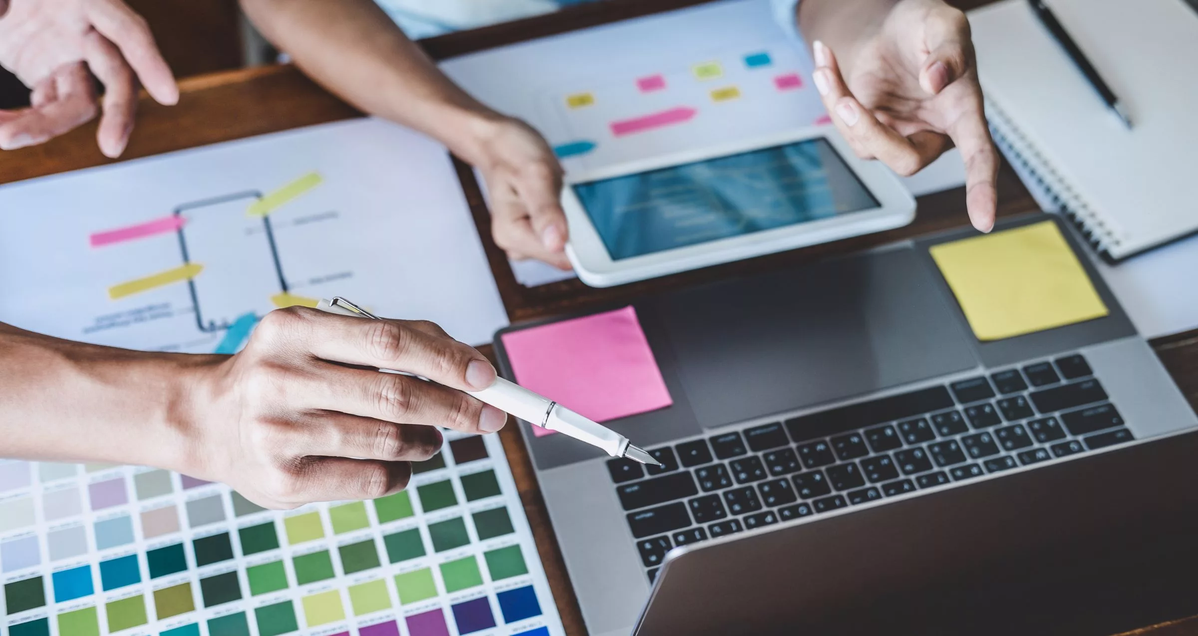 Image of people's hands pointing to colour swatches while considering colour schemes for their website