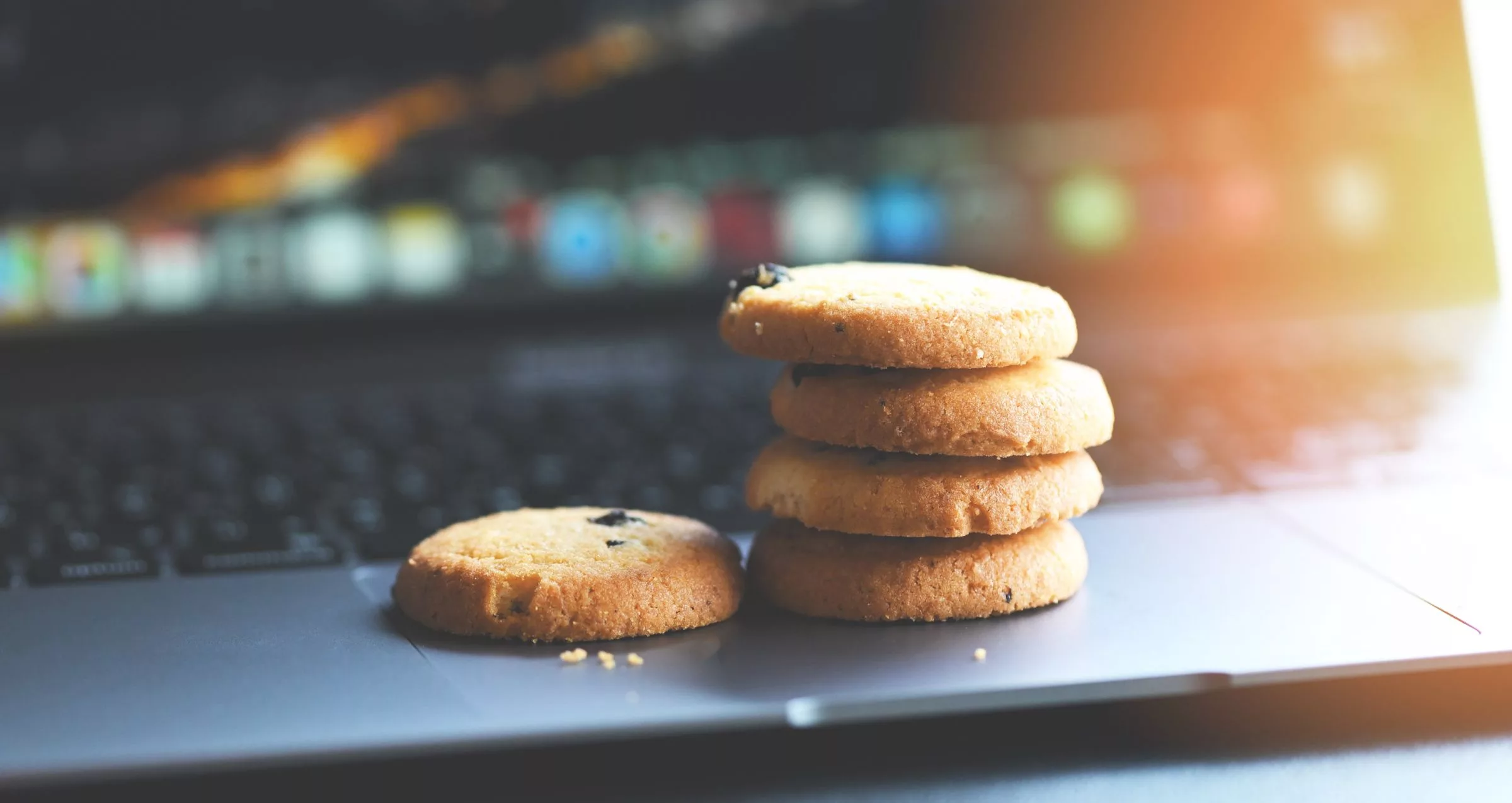 Image of cookies sitting on a laptop's keyboard to accompany blog post about cookie policies for websites.